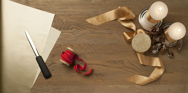裁纸刀带有红 金丝带和蜡烛的圣诞木桌背景