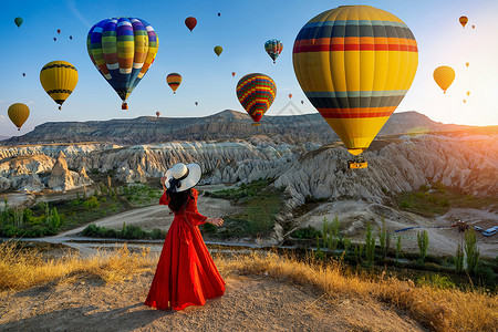 热气球和女孩美丽的女孩站在土耳其的卡帕多西亚 寻找热气球女性天空旅游日落阳光享受远足旅行冒险地标背景