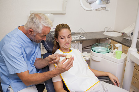 显示病人牙齿模型的牙科医生头发工作保健保健员快乐口腔科职业男性牙医女性背景图片