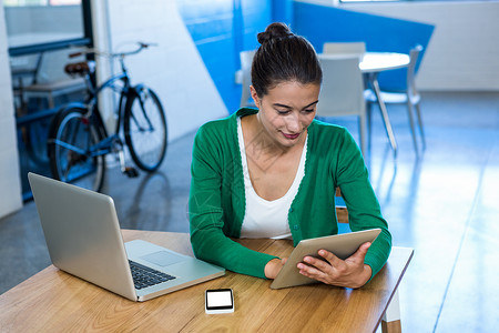 妇女使用数字平板电脑 手提笔记本电脑和手机微笑专注滚动公司商业管理人员职业职场沟通休闲专业的高清图片素材