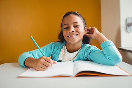 女孩在笔记本上写字混血女性幼儿园微笑学习早教课堂写作记事本童年小学高清图片素材