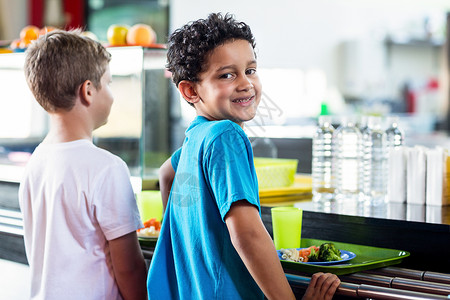 同学和同学站在食堂柜旁的中校男孩快乐高清图片素材