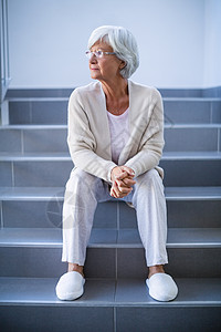 坐在楼梯上的深思熟虑的老女人高清图片