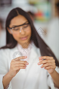 在校女生在实验室中用玻璃片做试验;背景图片