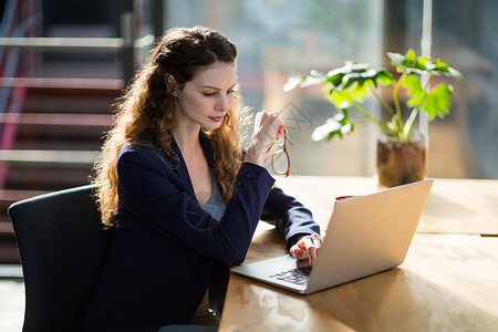 服务台使用膝上型电脑的女性商业主管技术笔记本眼镜现实办公室生活沟通专注互联网工作笔记本电脑高清图片素材