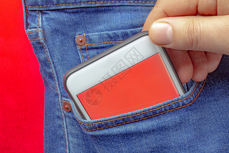一个人把带有红色屏幕的智能手机放在口袋里背景图片