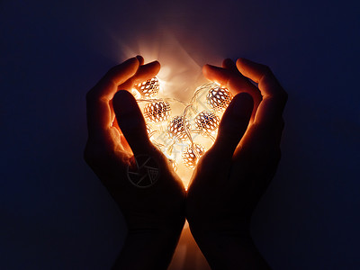 以心脏形状的手举着灯泡 金属灯泡魔法黑暗装饰品反射手势假期图案浪漫背景图片