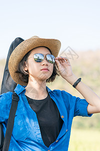 妇女戴着帽子走路 背着吉他包女孩头发草地音乐场地短发乐器女士青少年音乐家背景图片