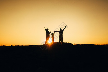 手太阳一个快乐的年轻幸福家庭 对抗橙色太阳的休眠沙丘男人日落天空生活女孩假期海滩自由沙漠背景