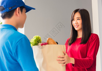 送货员做杂货 向女顾客提供新鲜食品导游男性船运服务蔬菜运输购物送货市场邮递员英俊的高清图片素材