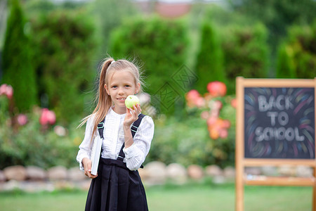 快乐的小女学生 在户外用黑纸板班级铅笔学校木板幼儿园公园玻璃桌子学习工作簿第一的高清图片素材