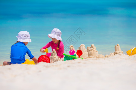 沙滩儿童沙玩具在热带度假期间玩沙滩玩具的女童幼女人数女孩幸福沙堡假期闲暇床垫海滨充气家庭海岸线背景