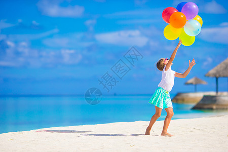 海滩女孩红气球可爱的小女孩在沙滩玩气球游戏女孩太阳镜享受海滨童年旅行假期乐趣蓝色情感背景