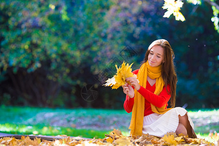 煮青梅女孩在美丽的秋天公园 带着黄色的青梅树叶在户外露脸的快乐少女季节母亲假期草地树叶晴天幸福友谊女士娱乐背景