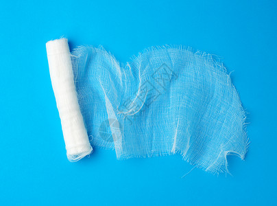 蓝色背景上的白纱布绷带卷背景图片