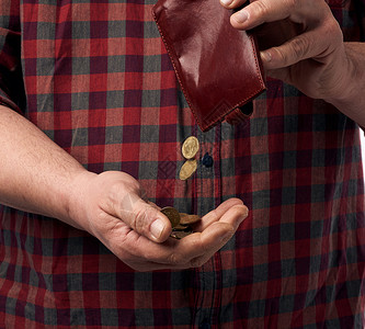 男人穿着红色衬衫 从棕色皮墙上扔出硬币薪水危机经济商业钱包皮革货币金属信用现金格里夫纳高清图片素材