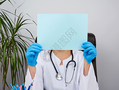 身穿白色医疗大衣的医生坐在棕色的桌子上工作室办公室从业者诊所蓝色手套卫生药物女士文档医师高清图片素材