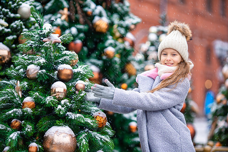 又是一年圣诞节新的一年 在雪地的fir tree树枝附近的小快乐女孩女孩枞树幸福帽子孩子季节传统童年喜悦森林背景