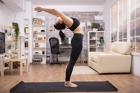 站立瑜伽青年瑜伽执业者站立后伸展房间女性运动装力量活动从业者女士姿势练习身体背景