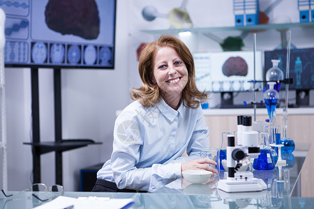 资金存管向在实验室用显微镜工作的高级医生妇女微笑背景