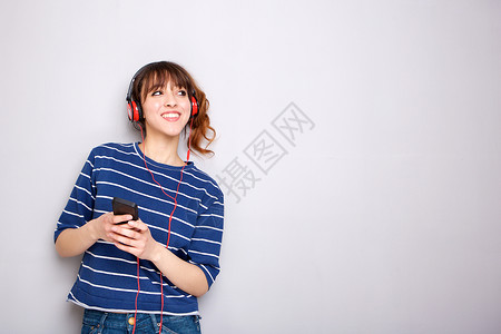 快乐的年轻女子用耳机和智能电话听音乐;肖像高清图片素材