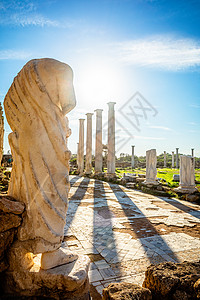 在萨拉米斯的太阳光和古老柱子下的大理石雕像背景