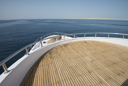 在一艘大型游艇的船首上观光航行巡航地平线海景甲板航海假期热带栏杆蓝色背景