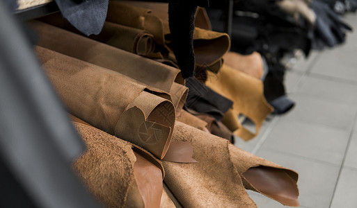 鞋子制作素材不同的皮革卷 彩色皮革碎片 天然棕红色皮革卷 制造箱包 鞋子 服装和配饰的原材料皮肤材料皮匠手工奶牛皮革加工衣服成套工厂生产背景