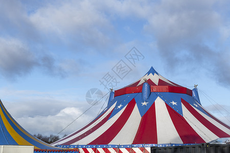 马戏团素材红白相间的马戏团帐篷 顶上是蓝星覆盖 顶着阳光明媚的蓝天 云朵派对公园吸引力喜悦竞技场乐趣节日横幅海报条纹背景