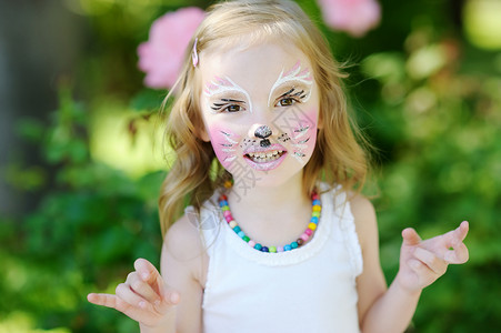 小画家哈咪猫脸涂着颜面的可爱小女孩创造力幼儿园喜悦金发猫咪舞会微笑童年艺术家面漆背景