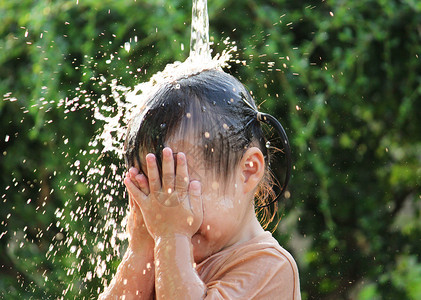 可爱的亚洲小女孩玩得开心 在夏令营里玩水喷水管晴天软管乐趣家庭后院女孩童年洒水器公园微笑孩子高清图片素材