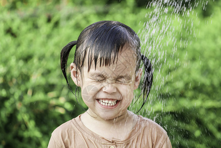 可爱的亚洲小女孩玩得开心 在夏令营里玩水喷水管孩子们花园家庭浴缸微笑软管公园童年乐趣飞溅湿的高清图片素材