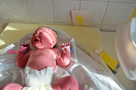新出生的婴儿-成功分娩后脐带剩余的女孩 真正的分娩和新生儿在医院 一名健康的新生女婴已接受检查并在分娩后采集婴儿脚印哭高清图片素材