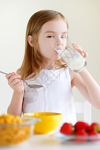 小女孩用牛奶吃麦片小吃午餐女孩乐趣水果谷物孩子微笑童年饮食早晨高清图片素材