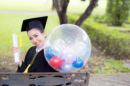 穿着学术服和学校服装的年轻快乐女毕业生肖像长袍文凭召集幸福证书气球学生教育成功研究生成熟高清图片素材