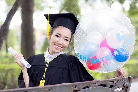 穿着学术服和学校服装的年轻快乐女毕业生肖像学习女孩研究生气球学士文凭召集帽子证书长袍人高清图片素材