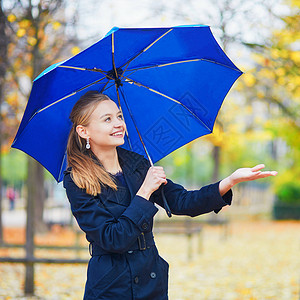 蓝色伞秋天或春季下雨日 在卢森堡巴黎花园的卢森堡花园中带蓝伞的年轻女子淋浴女士树叶叶子预报花园天气成人城市沉淀背景