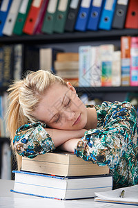 在图书馆睡觉的疲劳女青少年学生人数疲劳的高清图片素材