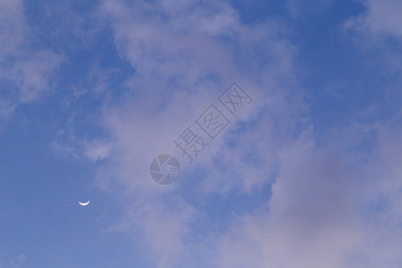 白昼的月亮笼罩着云层 在明亮的蓝天上满的高清图片素材