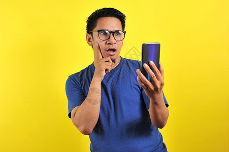 拥有智能手机的亚洲男子做思维手势背景人士男人震惊电话姿势广告黄色商业商务快乐高清图片素材