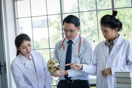 亚洲老师教学生理科和解剖学的亚洲教师骨骼学习男性实验室教授死亡颅骨男人大学教育女士高清图片素材