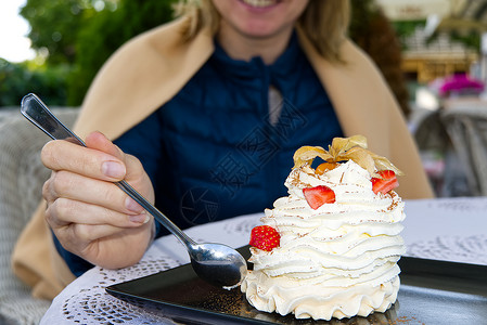 蓝莓奶油小蛋糕微笑的女人在餐厅里吃美丽的帕夫洛娃蛋糕 还有草莓和勺子烹饪鞭打奢华盘子食物酥皮杯子浆果甜点咖啡背景