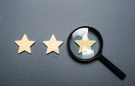 因表不凡三颗星和灰色背景上的放大镜 三星级认证 评级欺诈 餐厅或酒店的评级和状态 声望 高质量和可靠性背景