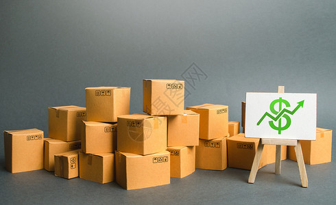大量纸箱和带有美元符号绿色向上箭头的标志 商品和产品生产的增长率 增加的经济指标 消费需求增加 贸易平衡堆高清图片素材
