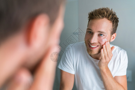 英俊的年轻男子在早上洗脸后将面部护理面霜涂在干净的皮肤上 以进行皮肤保湿护理 皮肤干燥问题 男士美容套路背景图片