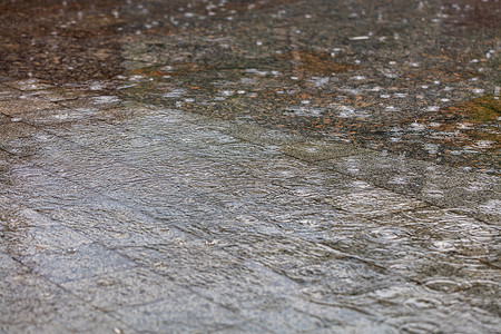 水面下雨时的同心圆环覆盖了城市人行道上的花岗岩地区高清图片