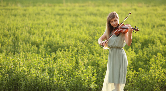 小提琴演奏时头发松发的浪漫女人 大自然的日落光音乐音乐家幸福夕阳制造商艺术晴天交响乐女孩艺术家背景图片