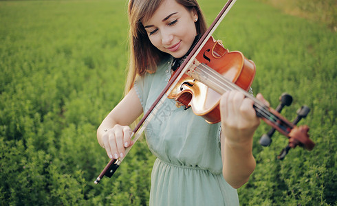 小提琴演奏时头发松发的浪漫女人 大自然的日落光女性女孩旋律古董交响乐爱好艺术乐器音乐家日落背景图片