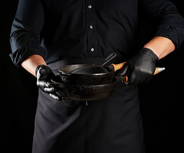 穿黑色制服和乳胶手套的男性厨师有一个空弹孔工作室厨房家庭煎锅金属职业男人厨具烹饪工作背景图片