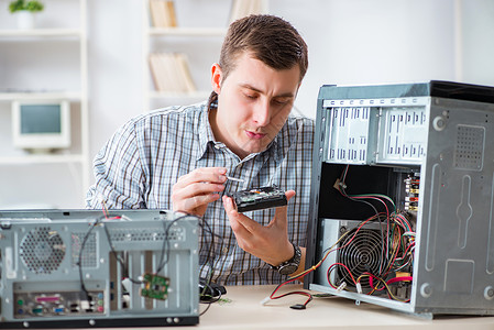 在车间修理计算机的年轻技工桌面展示技术员男人硬件母板替代品故障诊断电路个人电脑高清图片素材